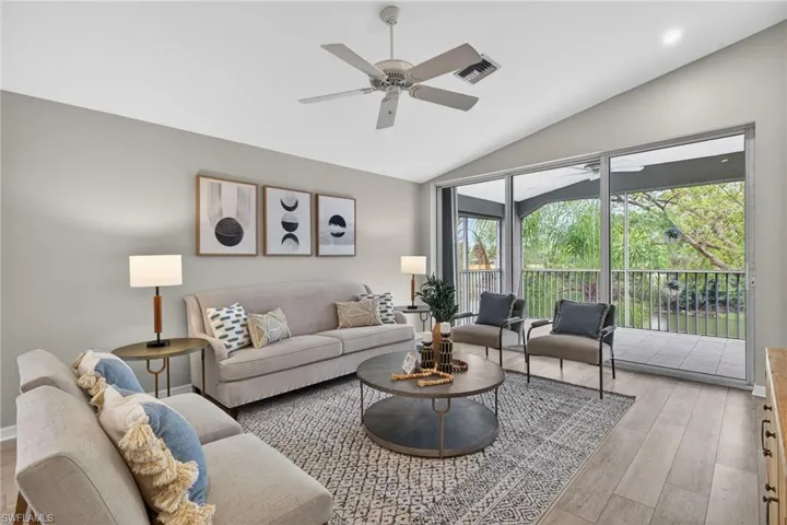 Living room featuring light wood-style floors, ceiling fan, and lofted ceiling