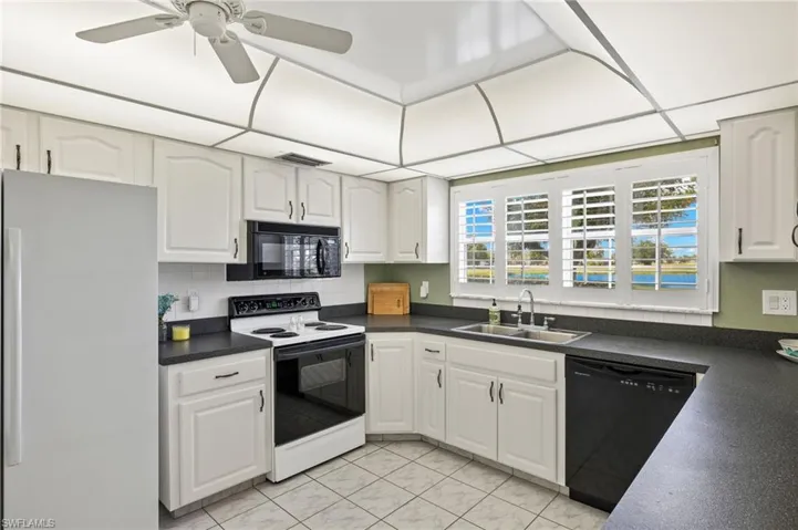 Kitchen featuring ceiling fan, black appliances, light tile floors, sink, and white cabinetry