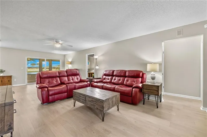 Living room featuring ceiling fan, a textured ceiling, and light wood-type flooring