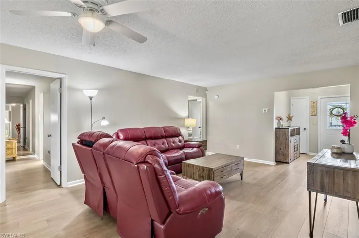 Living room with light hardwood / wood-style floors, a textured ceiling, and ceiling fan