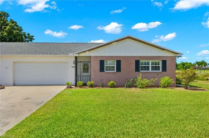 Ranch-style house with a garage and a front lawn