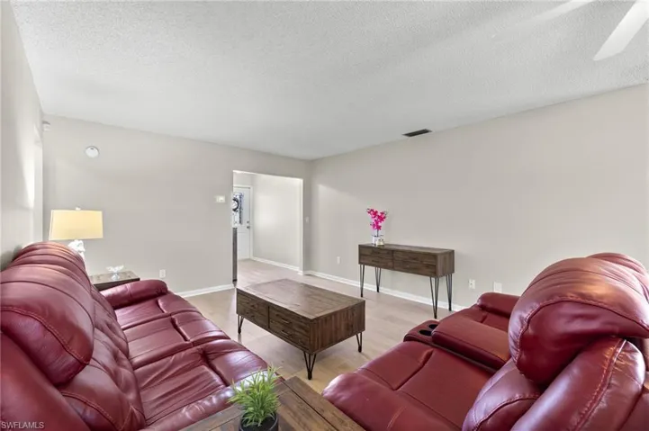 Living room featuring ceiling fan, a textured ceiling, and hardwood / wood-style flooring