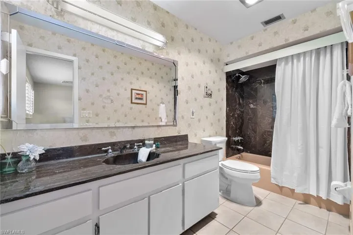 Full bathroom featuring tile flooring, shower / tub combo, vanity, and toilet