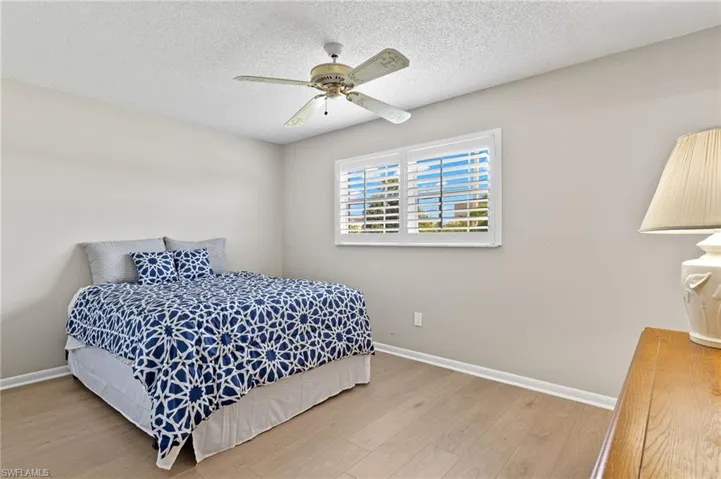 Bedroom featuring a textured ceiling, light wood-type flooring, and ceiling fan