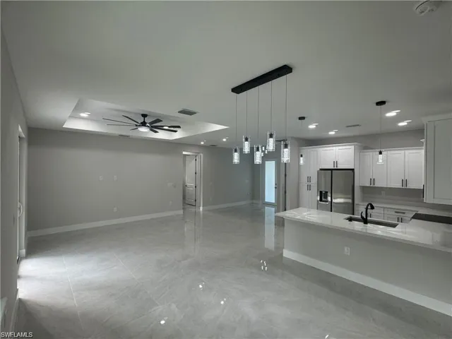 Spare room with light tile floors, ceiling fan, and a raised ceiling
