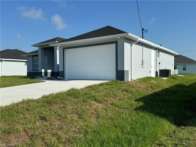 View of side of property featuring a garage, a yard, and central AC unit