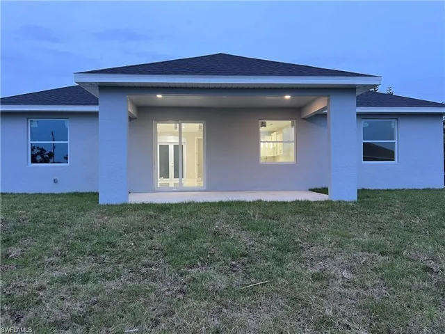 Back house at dusk with a patio and a yard