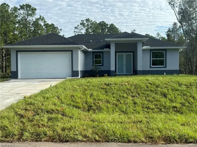 View of front facade featuring a garage and a front lawn