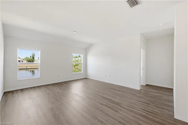 Unfurnished room with plenty of natural light, dark wood-style flooring, and lofted ceiling