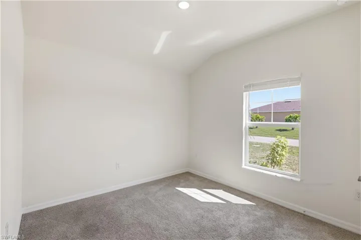 Spare room with vaulted ceiling and carpet