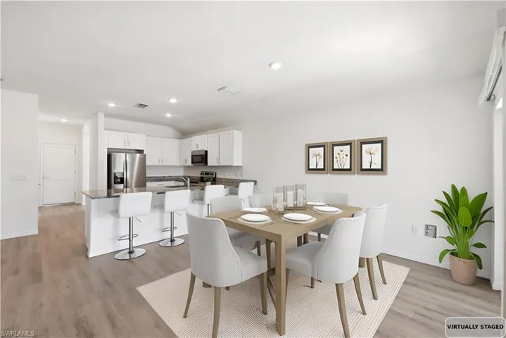 Dining room featuring light wood-style flooring, vaulted ceiling, and recessed lighting