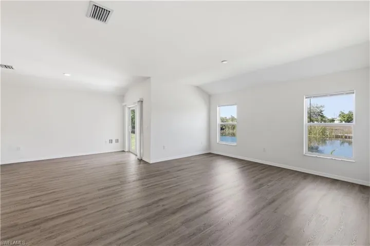 Spare room with dark wood-style floors, healthy amount of natural light, vaulted ceiling, and recessed lighting