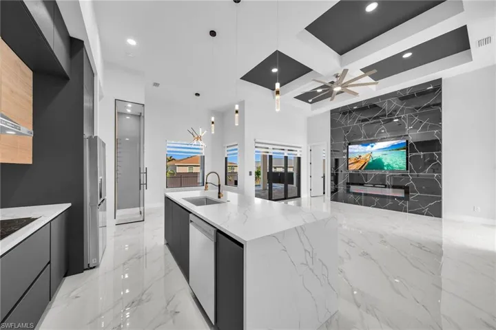 Kitchen with ceiling fan, sink, dishwasher, light stone counters, and pendant lighting