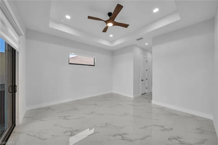 Empty room featuring ceiling fan and a raised ceiling