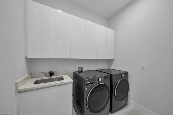 Laundry room featuring cabinets, separate washer and dryer, and sink