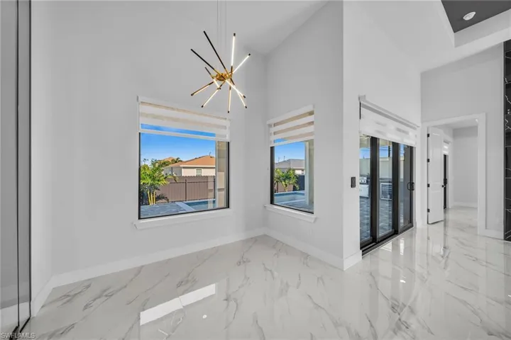 Unfurnished room featuring high vaulted ceiling and a notable chandelier