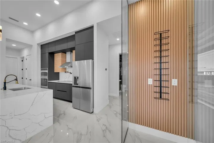 Kitchen with sink, wall chimney range hood, and appliances with stainless steel finishes