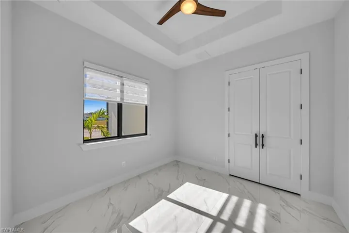 Unfurnished bedroom featuring a closet, a tray ceiling, and ceiling fan