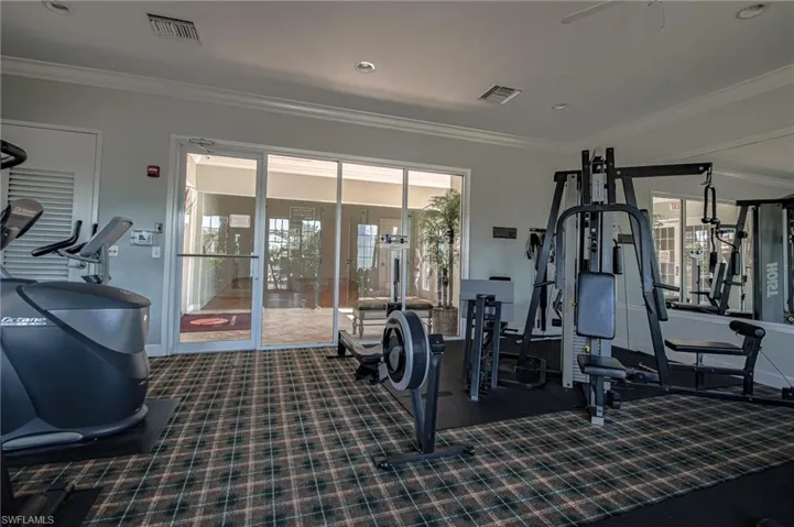 Workout area with dark colored carpet and crown molding