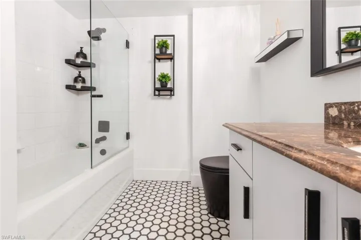 Full bathroom with tile floors, tiled shower / bath, vanity, and toilet