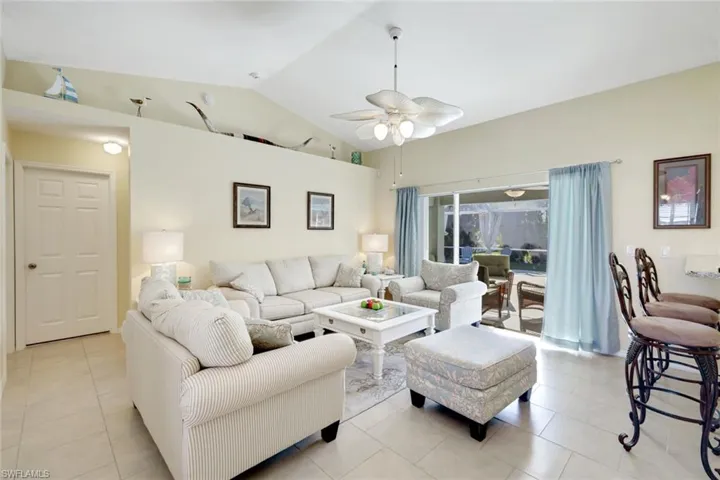 Living area with vaulted ceiling, sliding doors and views to the pool area