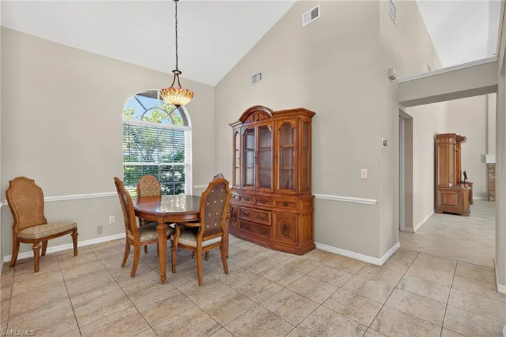 Dining space with high vaulted ceiling and light tile patterned floors