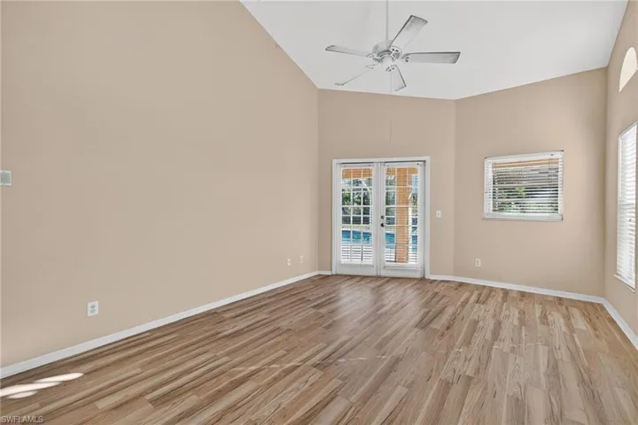 Unfurnished room with french doors, light wood-style flooring, ceiling fan, and high vaulted ceiling
