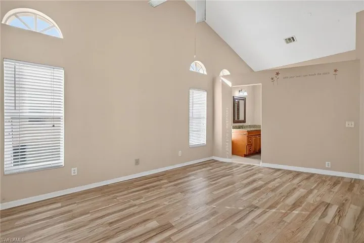 Spare room with high vaulted ceiling, light wood-type flooring, and a ceiling fan