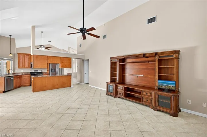 Unfurnished living room with high vaulted ceiling, light tile patterned floors, and ceiling fan