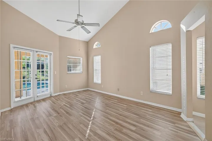 Spare room with high vaulted ceiling, light wood-style flooring, a ceiling fan, and french doors