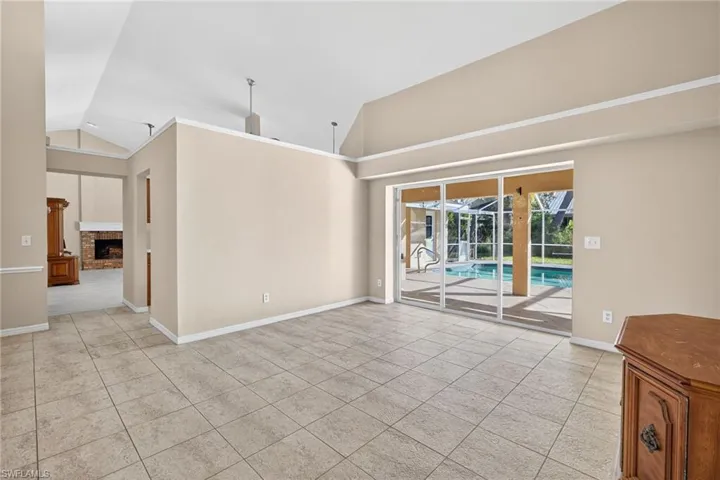 Spare room with a brick fireplace, a sunroom, light tile patterned floors, and high vaulted ceiling