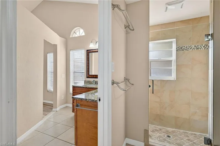 Bathroom featuring vanity, light tile patterned floors, and a stall shower