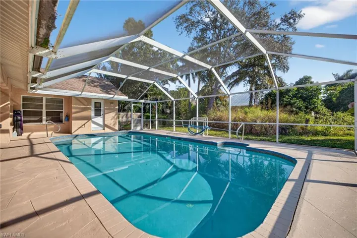 Swimming pool featuring glass enclosure, a patio, and a sunroom