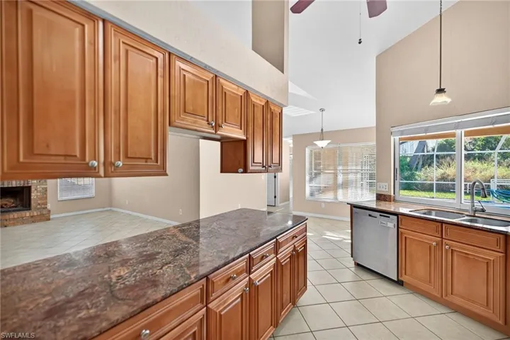 Kitchen featuring light tile patterned floors, dark stone counters, brown cabinets, a high ceiling, and ceiling fan