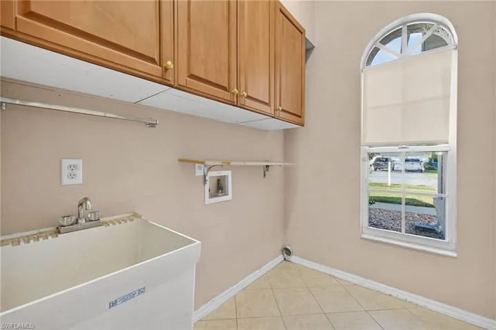 Laundry room with light tile patterned floors, hookup for a washing machine, and cabinet space