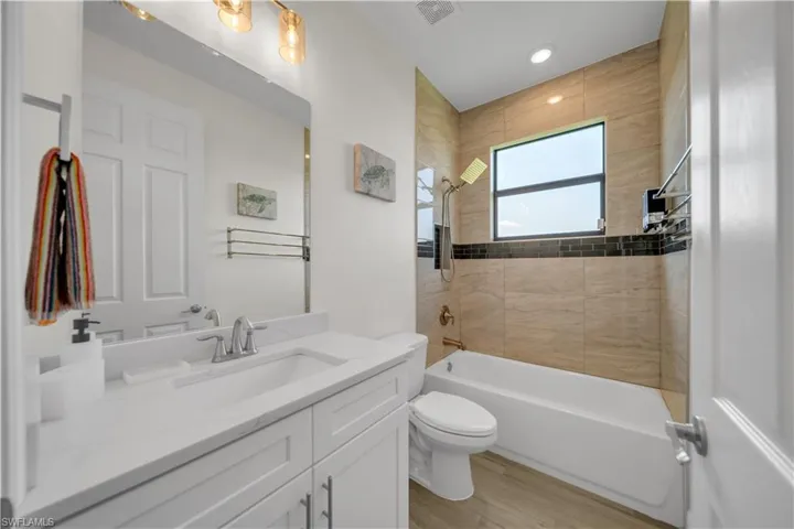 Full bathroom with vanity, toilet,  shower combination, wood finished floors, and recessed lighting