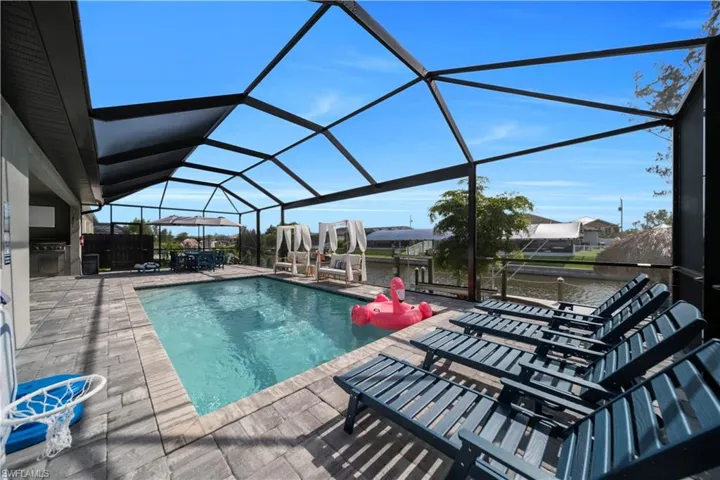 Outdoor pool featuring a patio area, exterior kitchen, and glass enclosure