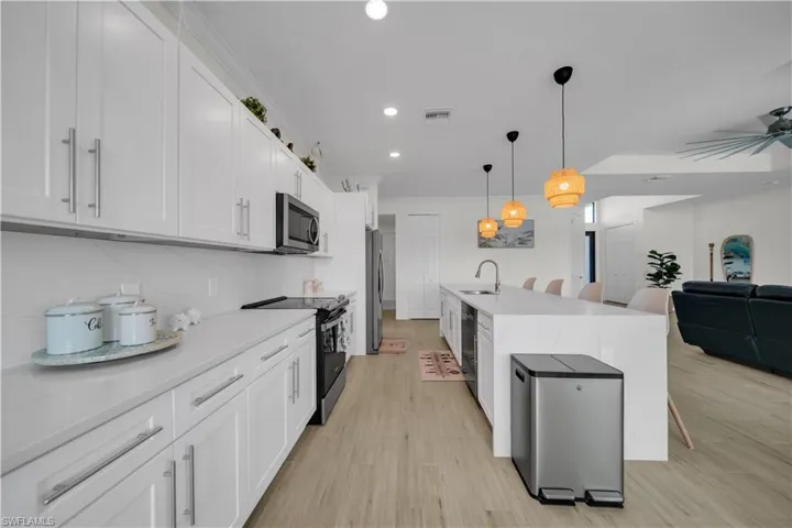 Kitchen with appliances with stainless steel finishes, open floor plan, light countertops, white cabinets, and recessed lighting