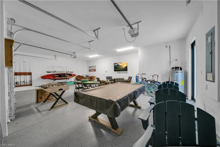 Playroom with water heater, a garage, billiards table, speckle patterned floor, and electric panel