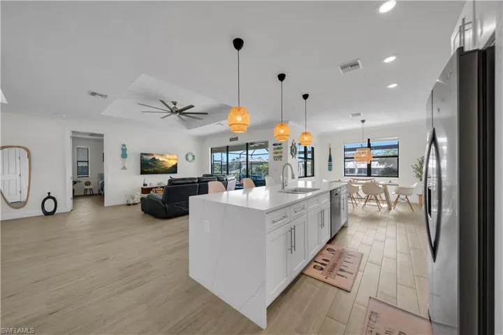 Kitchen with appliances with stainless steel finishes, a sink, light wood-style flooring, recessed lighting, and white cabinets