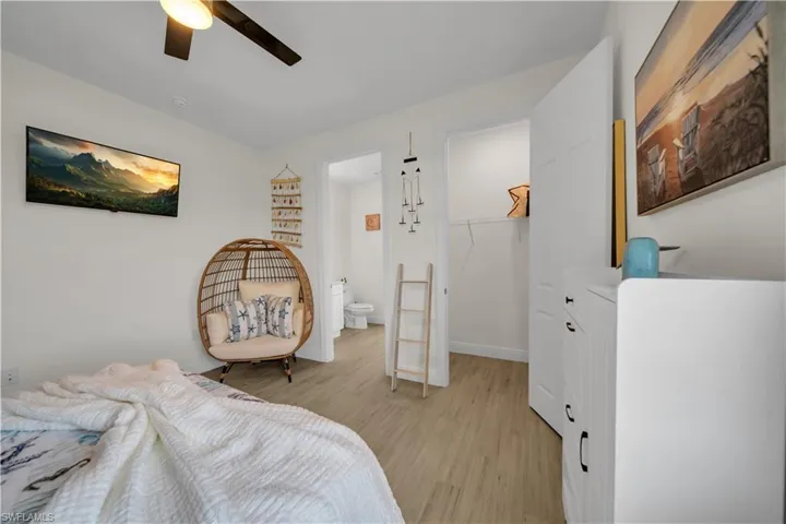 Bedroom featuring light wood-style floors, a walk in closet, a closet, a ceiling fan, and baseboards