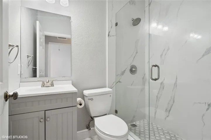 Bathroom with vanity with extensive cabinet space, walk in shower, and toilet