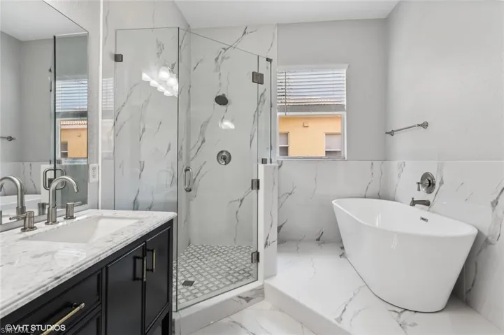 Bathroom featuring independent shower and bath, tile walls, tile floors, and large vanity