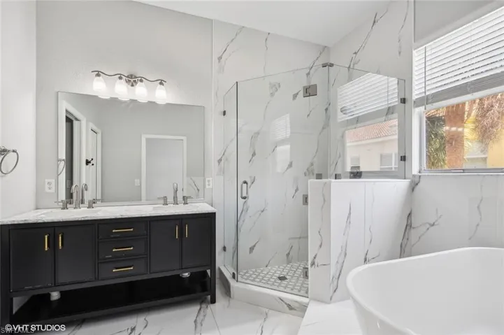 Bathroom with tile flooring, an enclosed shower, and double sink vanity