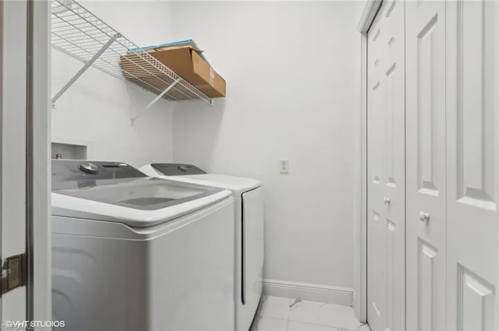 Laundry room featuring washing machine and clothes dryer and light tile floors