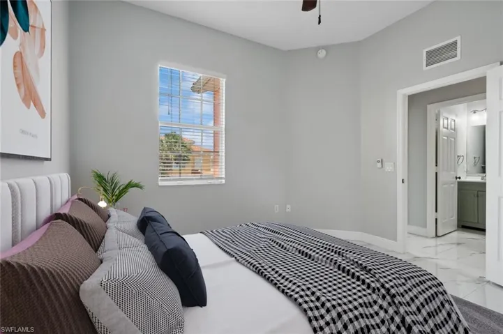 Bedroom with ensuite bathroom, ceiling fan, and light tile floors