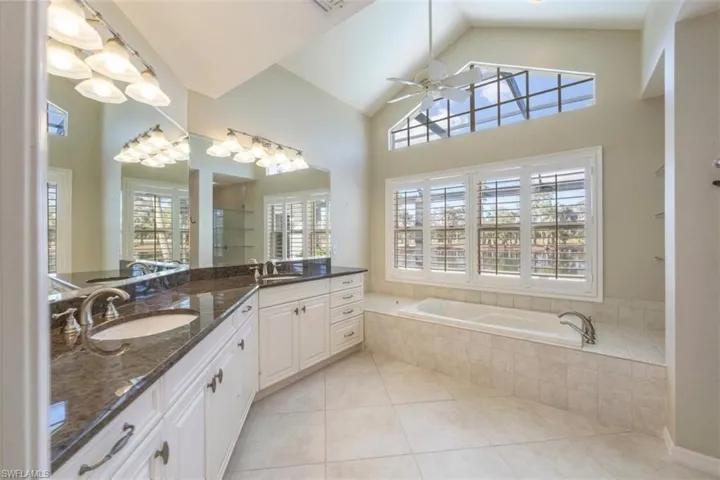 Bathroom featuring double vanity, plenty of natural light, a stall shower, a bath, and high vaulted ceiling