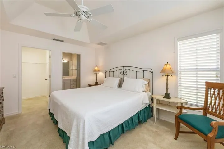 Bedroom with light carpet, ceiling fan, and connected bathroom