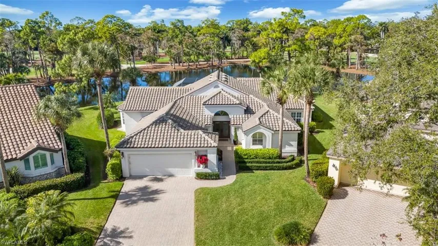 Arial view of home featuring stucco siding, a water view, view of scattered trees, and an attached garage