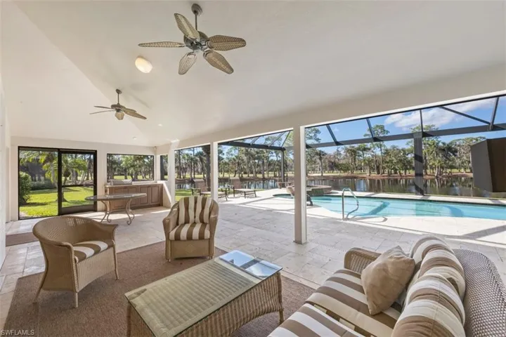 View of pool and Spa with an outdoor living space, a patio area, a water view, a sunroom, and a lanai